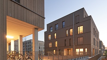 Night shot of two multi-storey wooden buildings.