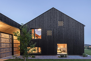 Foto eines modernen Holzhauses mit Holzfassade. Nachtaufnahme.