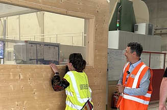 Zwei Personen in der Fertigungshalle von ZÜBLIN Timber. Sie stehen an einem Holzelemeht.