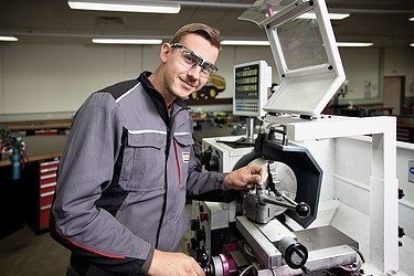 Foto eines jungen industriemechanikers, der an einer Maschine steht.