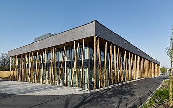 Foto eines Hauses mit Flachdach und vorgelagerten Staketen aus einer verglasten Pfosten-Riegel-Konstruktion.