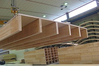 Mehrgeschossiger Holzbau bei ZÜBLIN Timber. Rippen- und Kastenelemente. Foto eines Rippenelements am Kran in der Produktionshalle von ZÜBLIN Timber.
