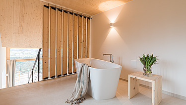 Foto eines Badezimmers. Man sieht eine Badewanne und viele Holzoberflächen.