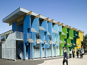 Foto eines Schulgebäudes mit bunten Fassadenelementen aus Furnierschichtholz.