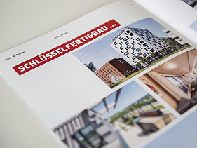 Foto der Innenseite der Image-Broschüre von ZÜBLIN Timber. Man sieht mehrere Gebäude aus Holz und die Überschrift Schlüsselfertigbau.