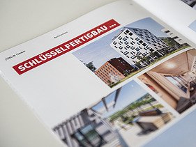 Foto der Innenseite der Image-Broschüre von ZÜBLIN Timber. Man sieht mehrere Gebäude aus Holz und die Überschrift Schlüsselfertigbau.