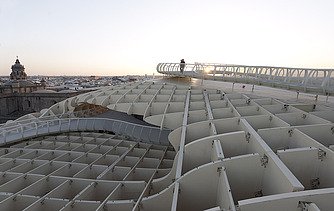 Foto eines Skywalkes des Metropol Parasols in Sevilla Spanien. Man sieht eine Person in der Abenddämmerung  auf dem Skywalk stehen.