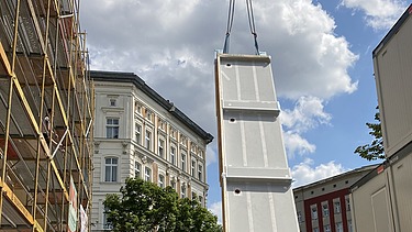 Foto der Holzbaumontage in der Stendaler Straße in Berlin. Man sieht ein großes LENO-ADD-Holzelement am Kran.