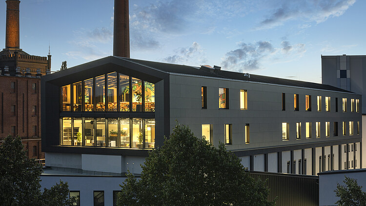 Night shot of the wooden extension to the new office building of the Maisel brewery in Bayreuth.