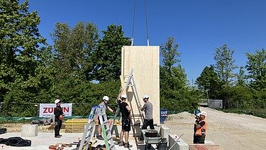 Construction site photo showing the assembly of the first cross-laminated timber elements.