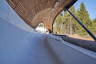 Foto einer Rodelbahn. Man sieht eine Holzüberdachung und nur einen Ausschnitt davon