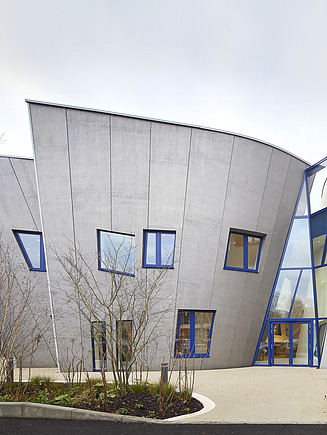 Exterior view of the Maggie Center in London. You can see a curved wooden building.