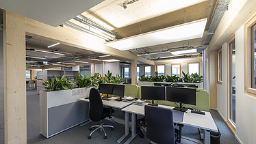 Innenraumfoto des Büroneubaus T3 in Aichach. Zu sehen sind Bildschirmarbeitsplätze.