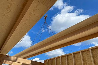 Foto eines großen Holz-Rippenelements auf einer Baustelle, blauer Himmel