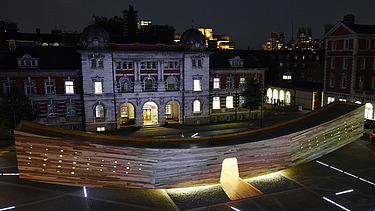 Night shot of the curved wooden sculpture The Smile in London. The wooden box can be walked on and is intended to represent a smiling mouth.