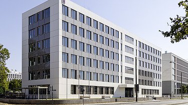 Foto eines mehrgeschossigen Wohnungsbaus aus Holz mit weißer Fassade.