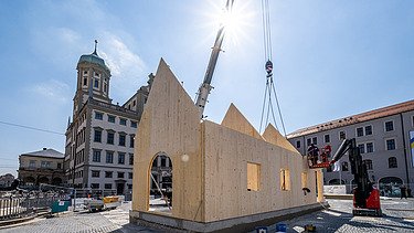 Photo of the NEXT500 pavilion on Augsburg's market square. You can see the assembly of the LENO elements.