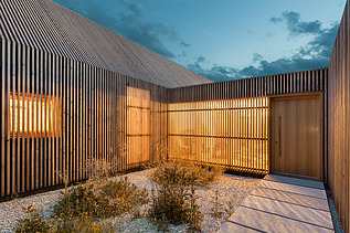 Foto eines modernen Holzhauses in U-Form mit Holzfassade. LENO-BSP.