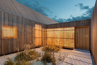 Foto eines modernen Holzhauses in U-Form mit Holzfassade. LENO-BSP.