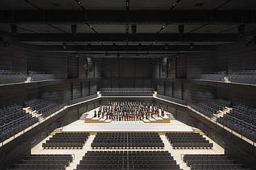 Interimsspielstätte Gasteig München Foto der Interimsspielstätte Gasteig in München. Zu sehen ist der bestuhlte Bühnenraum mit Orchester.