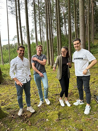 Foto von jungen Personen, die im Wald stehen und scherzen.