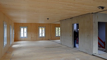 Foto einer Innenaufnahme eines mehrgeschossigen Wohngebäudes im Rohbau. Man sieht viele Holzoberflächen.