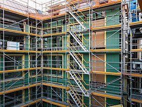 Foto des Rohbaus VINZENT in München. Zu sehen ist ein eingerüstetes, mehrgeschossiges Gebäude.