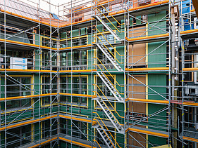 Photo of the VINZENT building shell in Munich. You can see a scaffolded, multi-storey building.