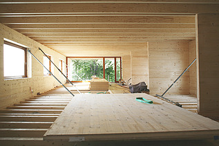 Photo of a timber building shell. The photo shows LENO cross-laminated timber walls and a ribbed timber ceiling.