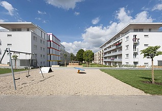 Aufstockung Konradsiedlung, Regensburg Foto zweier mehrgeschossigen Gebäude mit Garten davor. Aufstockungen aus Holz.