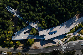 Timber engineering and free-form surfaces from ZÜBLIN Timber. Ruhestein visitor center project Aerial view of the visitor center in Ruhestein. You can see a building complex in the middle of a forest.