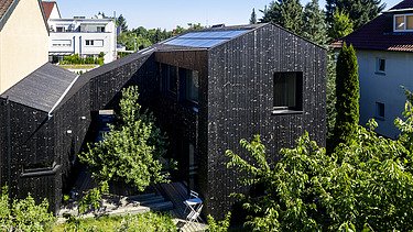 Foto eines Wohnhauses aus Holz und mit dunkler Holzfassade.