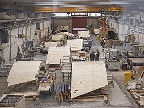 Photo of a production hall with several curved wooden shells