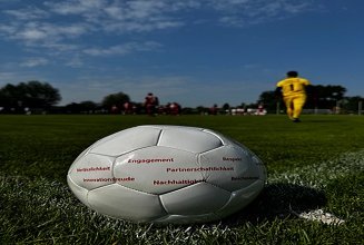 Foto mit einem weißen Fußball auf dem Rasen. Auf dem Fußball stehen in roter Schrift die ZÜBLIN-Werte.