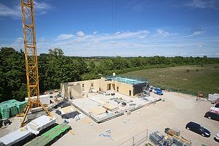 Baustellenfoto, auf dem die Montage der ersten Brettsperrholzelemente zu sehen ist.