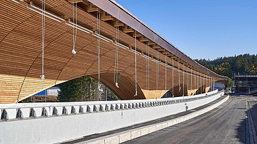 Foto einer Rodelbahn. Man sieht eine Holzüberdachung und nur einen Ausschnitt davon