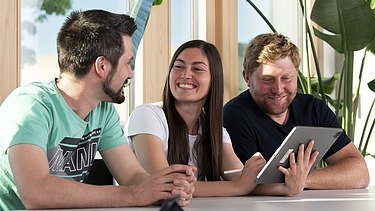 Foto von zwei Männern und einer Frau, die sich in einem Besprechungsraum unterhalten
