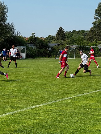 Photo of a soccer field with several male and female soccer players.