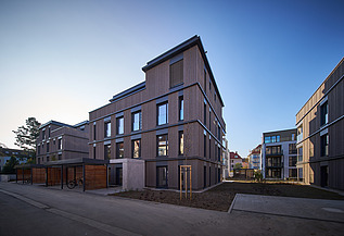 Foto eines mehrgeschossigen Wohngebäudes mit Holzfassade.