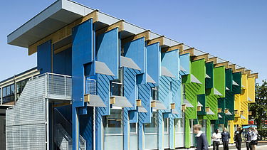 Foto eines Schulgebäudes mit bunten Fassadenelementen aus Furnierschichtholz.