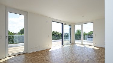 Photo of a bright, empty interior with white walls and wooden floor.