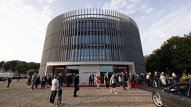 Foto des Globe Theaters in Coburg. Man sieht ein rundes Gebäudes mit Menschen davor.