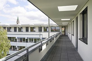 Foto einer Nahaufnahme einer Aufstockung aus Holz. Man sieht den Zugang zu den einzelnen Wohnungen.