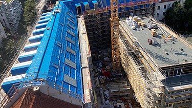 Photo of the VINZENT building shell in Munich. A scaffolded, multi-storey building can be seen from above.