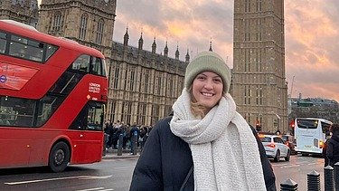 Photo of a young woman in London. Big Ben can be seen in the background.