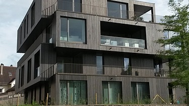 Photo of a multi-storey residential building with a wooden façade.