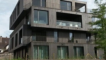 Photo of a multi-storey residential building with a wooden façade.