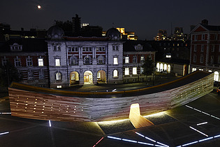 Night shot of the curved wooden sculpture The Smile in London. The wooden box can be walked on and is intended to represent a smiling mouth.