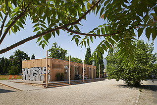 Photo of a wooden building with a flat roof. You can also see graffiti on the wooden façade.