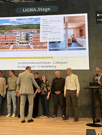 Foto von Menschen auf der Bühne. Preisverleihung Deutscher Holzbau Preis 2025
